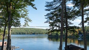 A lakeside cabin with a dock, surrounded by trees and a forested hillside. - Come stay at our four season resort! (Weare)
