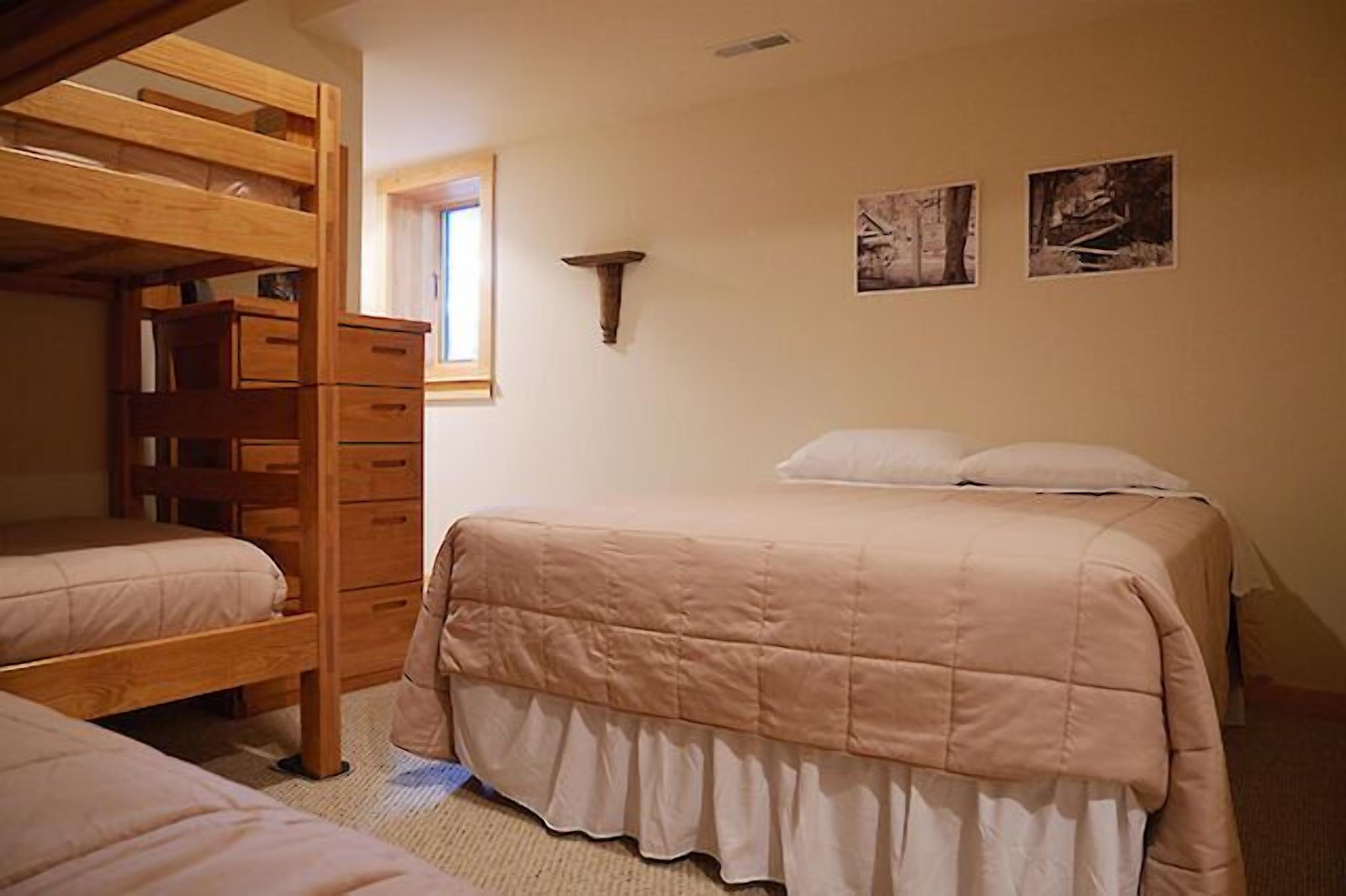 Un dormitorio con literas, un aparador y dos cuadros en la pared.