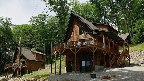 A large log cabin with a balcony and a separate building with a porch. - Come stay at our four season resort! (Weare)