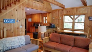 L’intérieur d’une cabane en bois comprend un coin repas, une cuisine et un escalier menant à un niveau supérieur.