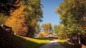 A pathway leading to a lodge with a prominent wooden structure, surrounded by trees with autumn foliage. - Come stay at our four season resort! (Weare)