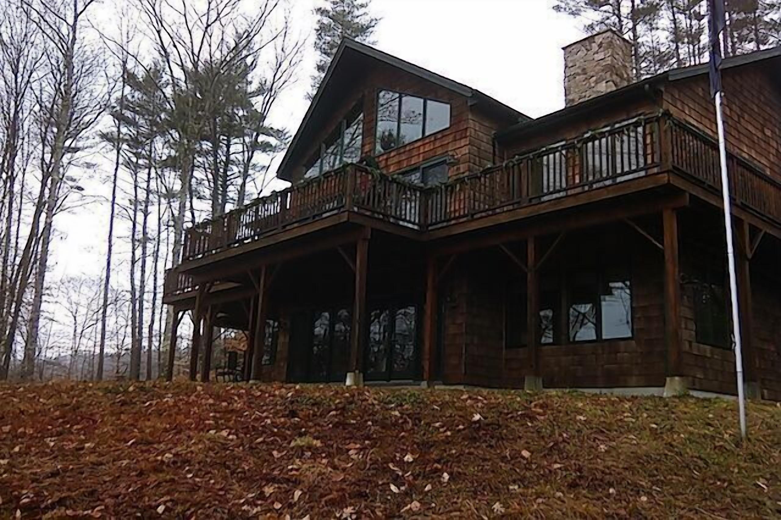 A large, two-story wooden cabin with a balcony and multiple windows.