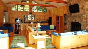 A log cabin interior with a kitchen, living room, and stone fireplace. - Come stay at our four season resort! (Weare)