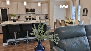 A modern kitchen with a central island, bar stools, and pendant lighting.