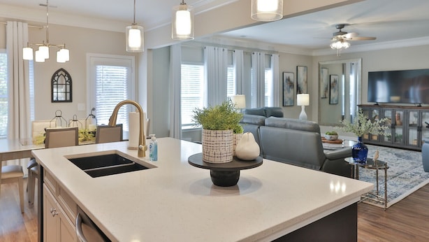 A modern kitchen with a central island, pendant lights, and a dining area with a chandelier.