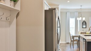 A modern kitchen with a built-in refrigerator, wooden flooring, and a bench with storage drawers.