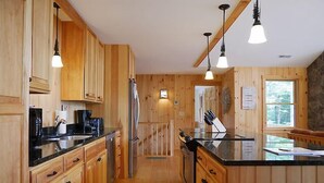 Una cocina tipo cabaña de madera, con armarios de madera, una encimera negra y luces colgantes.