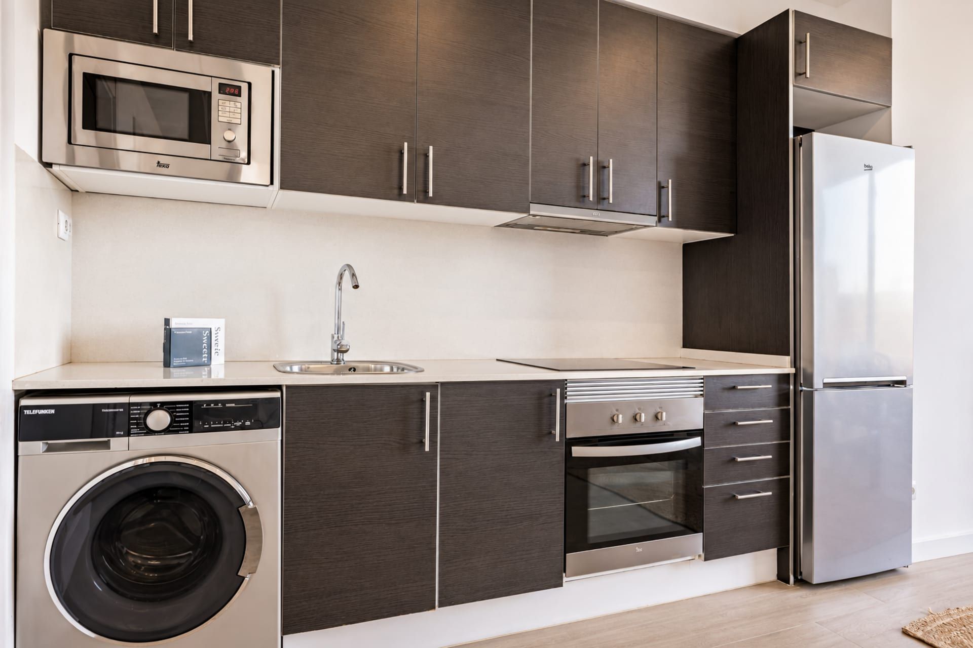 Une cuisine moderne équipée d’un lave-linge, d’un four à micro-ondes, d’un réfrigérateur et d’une cuisinière.