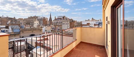 A balcony with a metal railing overlooking a cityscape with various buildings.