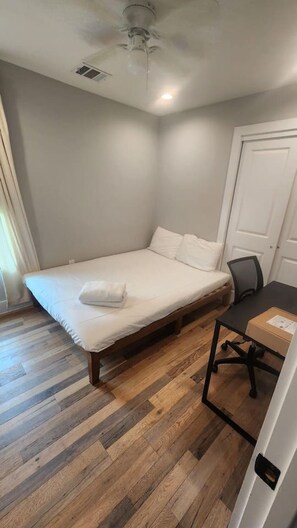 Un dormitorio con cama, escritorio y puerta.