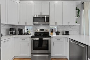 A modern kitchen with white cabinetry, stainless steel appliances, and a marble backsplash. - Modern 3BR Home | 5 Min to Downtown & SXSW (Austin)