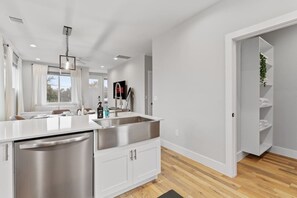 Una cocina moderna con un lavamanos de acero inoxidable, armarios blancos y piso de madera.