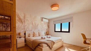 Ein modernes Schlafzimmer mit einem großen Bett, einem Nachttisch aus Holz, einem Sessel und einem Fenster mit Blick.