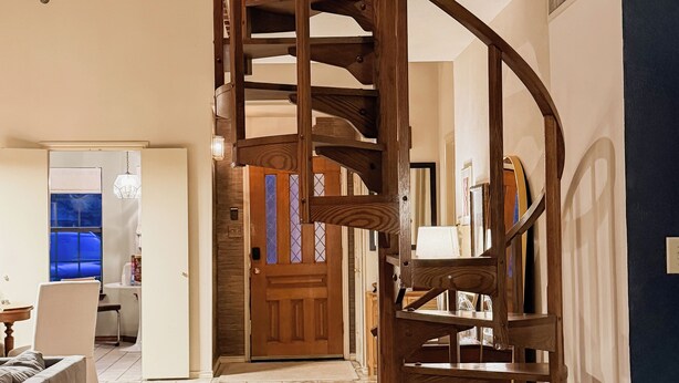 A spacious room with a wooden spiral staircase leading to an upper level.