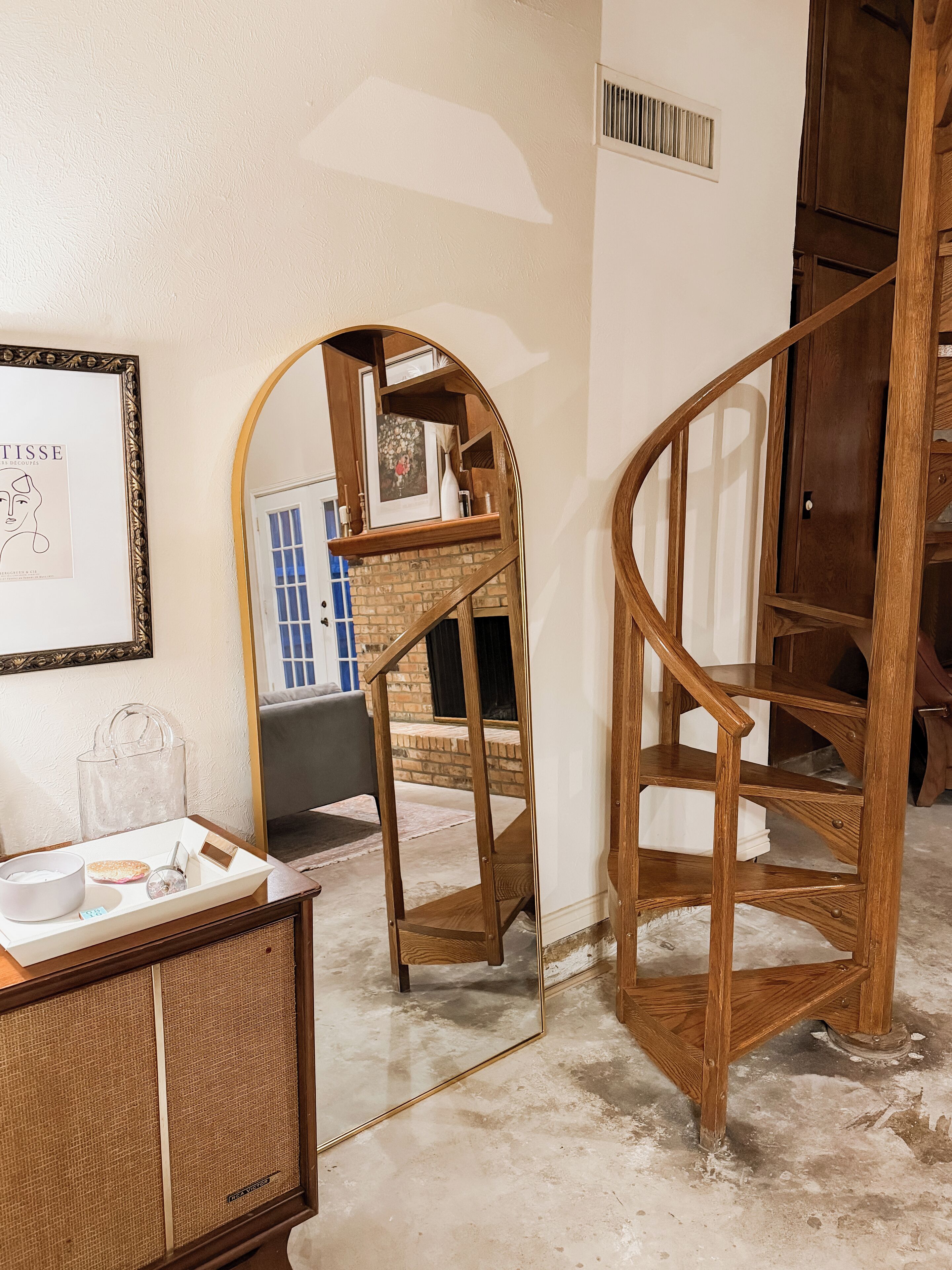 A room with a wooden staircase, a framed picture on the wall, and a small table with a tray.