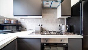 A modern kitchen with a microwave, toaster, kettle, and oven.