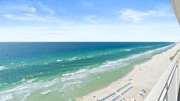A beach view from a balcony with a clear sky.