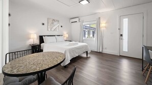 A modern bedroom with a bed, bedside tables, a round dining table, and a window with curtains.