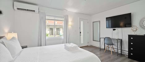 Una habitación de hotel con cama, escritorio, televisión y cómoda.