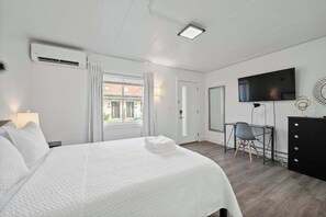 Una habitación de hotel con cama, escritorio, televisión y cómoda.