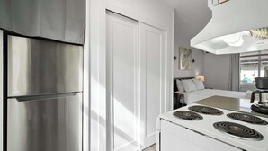 A modern kitchen with a stainless steel refrigerator, a white stove, and a dining area with a table and chairs.