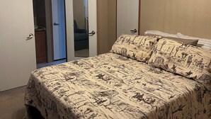 A bedroom with a bed, a ceiling fan, and two doors.