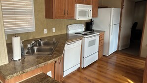 A kitchen with wooden cabinets, a white stove, a microwave, and a refrigerator.