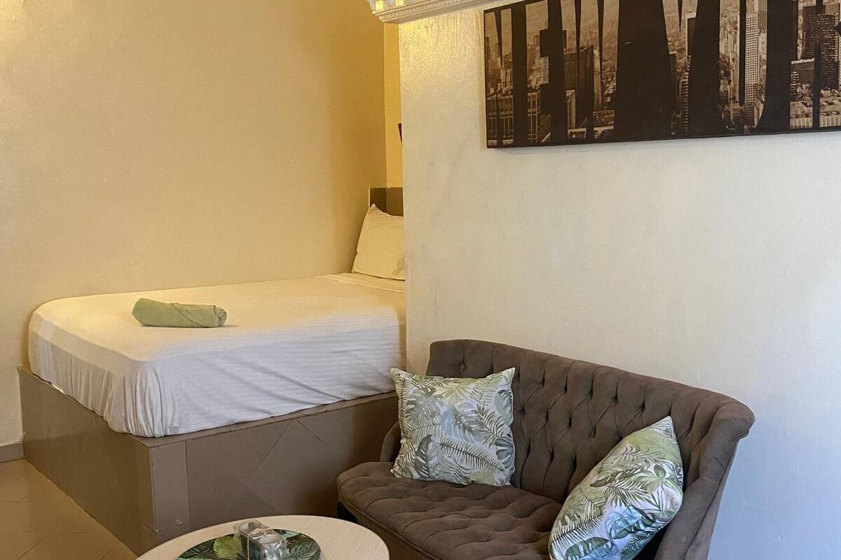 A small room with a bed, a sofa, and a small table.