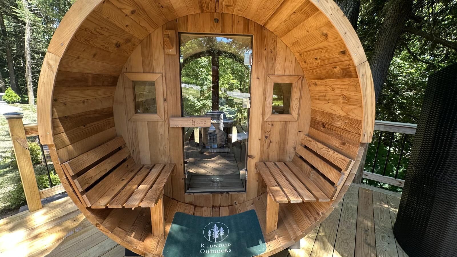 A wooden sauna with benches and a central pillar, surrounded by a deck.