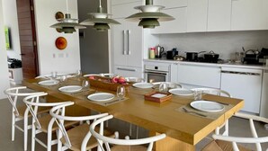 A modern kitchen with white cabinets, a wooden island, and pendant lighting. - Yeguas 102 by Wynwood House (Anapoima)