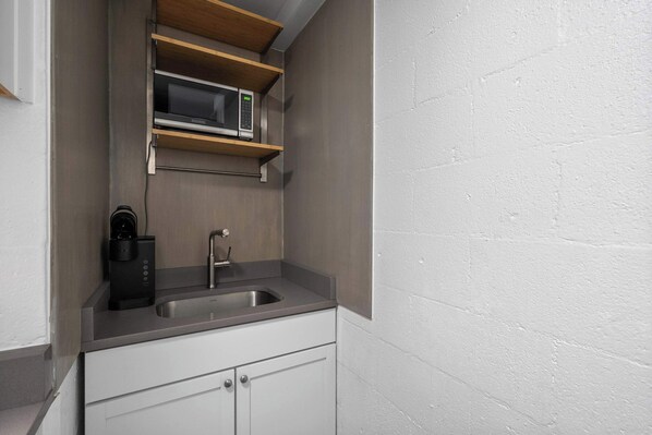 A compact kitchen with a built-in microwave, a coffee maker, and a sink.