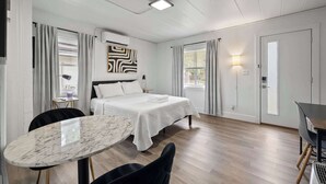 A modern hotel room with a large bed, a marble table, and a dining area. - Chic City Retreat 97 Sleeps 2! (Columbus)