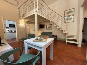 A modern interior with a dining area, kitchen, staircase, and a bed.