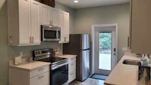A modern kitchen with white cabinets, a microwave, a stainless steel refrigerator, and an oven.