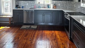 A modern kitchen with dark cabinets, stainless steel appliances, and patterned backsplash.
