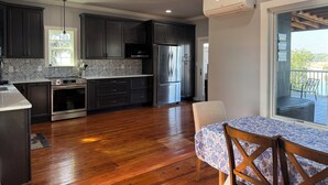 A modern kitchen with dark cabinets, stainless steel appliances, and a wooden floor.