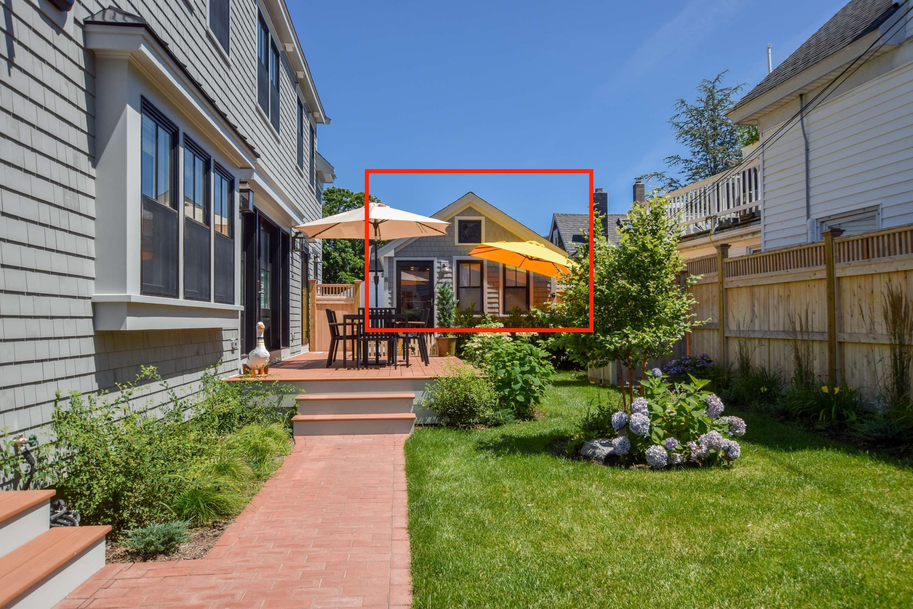 A residential backyard with a patio, outdoor furniture, and a garden.