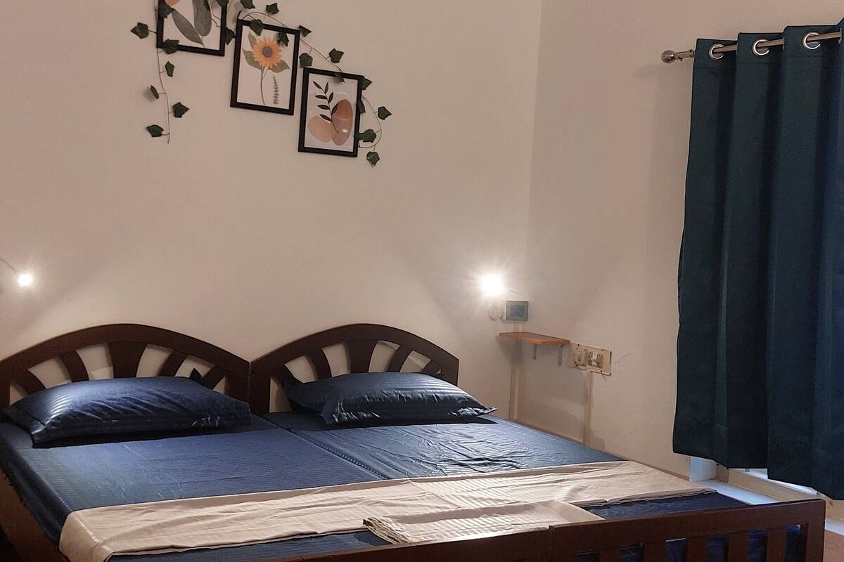 A bedroom with a wooden bed, a ceiling fan, a wall-mounted light, and a patterned rug.