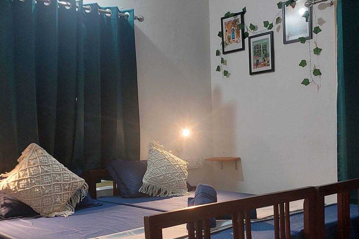 A room with a bed, a table, chairs, a rug, and a wall with pictures and a mirror.