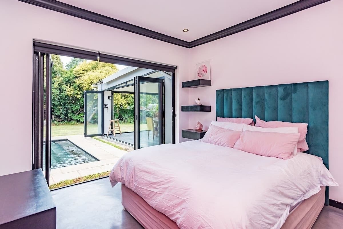 A bedroom with a large bed, a sliding glass door leading to a patio, and a teal headboard.