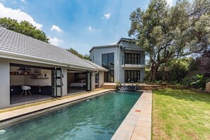 A modern house with a swimming pool, a covered patio, and a large tree in the backyard. - The Urban Sanctuary Boutique Hotel  (Randburg)