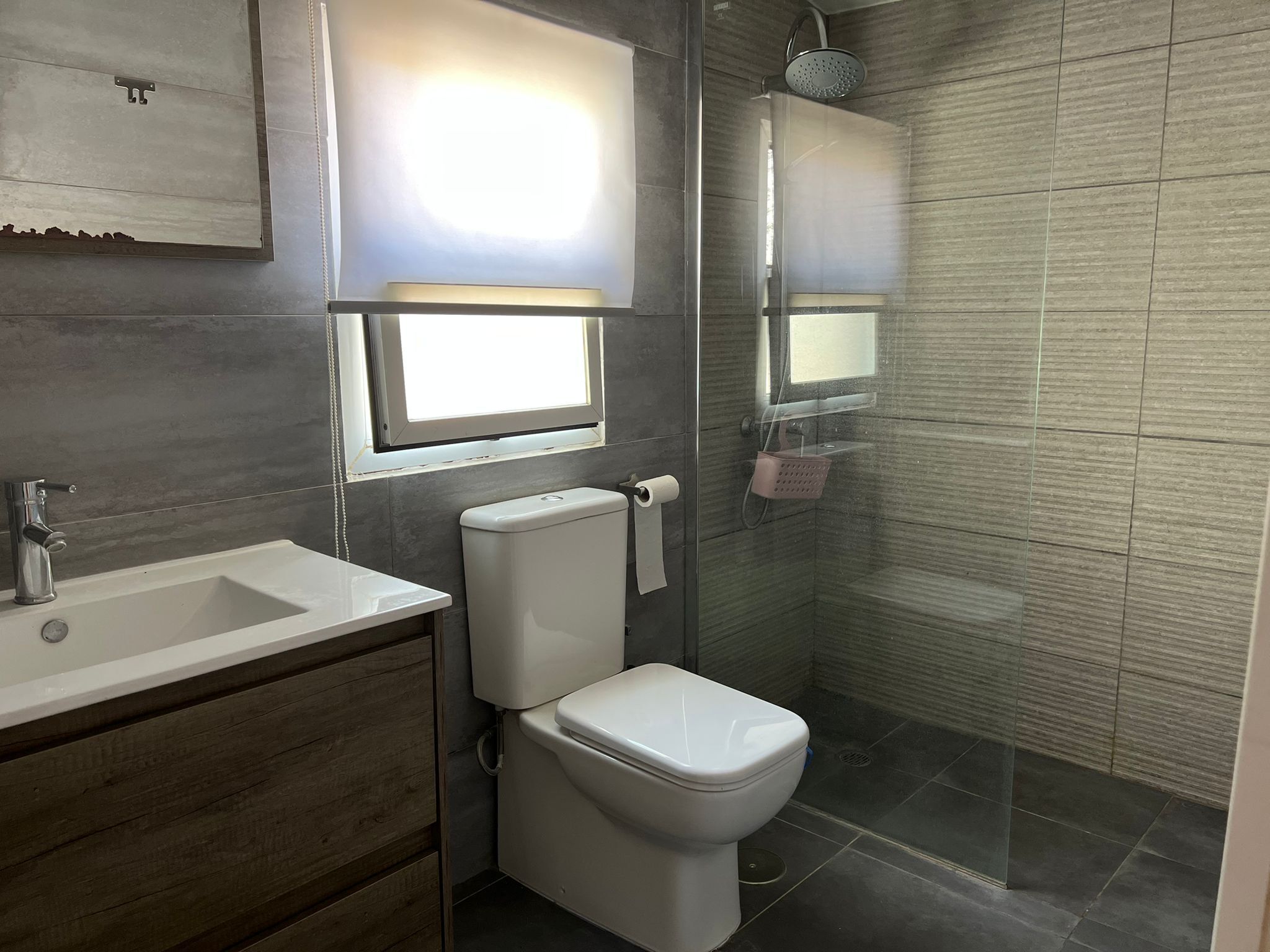 A modern bathroom with a sink, toilet, and glass shower enclosure.