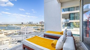 Een balkon met twee bedden, uitzicht op de stad en een modern gebouw op de achtergrond.