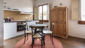 A compact kitchen with a dining area, wooden cabinets, and a window providing natural light.