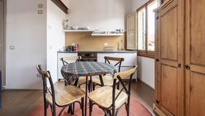 A compact kitchen with a dining table, four chairs, wooden cabinets, and a window providing natural light.