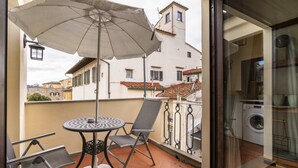Ein Balkon mit Tisch, Stühlen und Sonnenschirm.