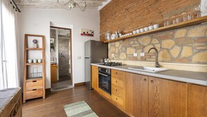 Eine Küche mit Holzschränken, einer Steinrückwand und einem eingebauten Backofen.