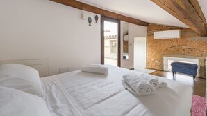 Ein Schlafzimmer mit einem großen Bett, einem Steinkamin und Holzbalken an der Decke.