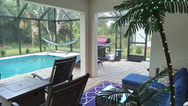 A covered outdoor area with a pool, seating, and a hammock. - Maximo Vacation

 (North Port)