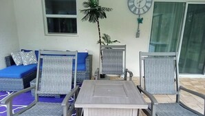 A patio area with a table and four chairs, a sofa set, a potted plant, and a wall clock. - Maximo Vacation

 (North Port)